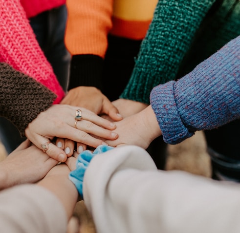 person in red sweater holding babys hand