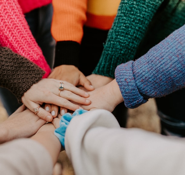 person in red sweater holding babys hand