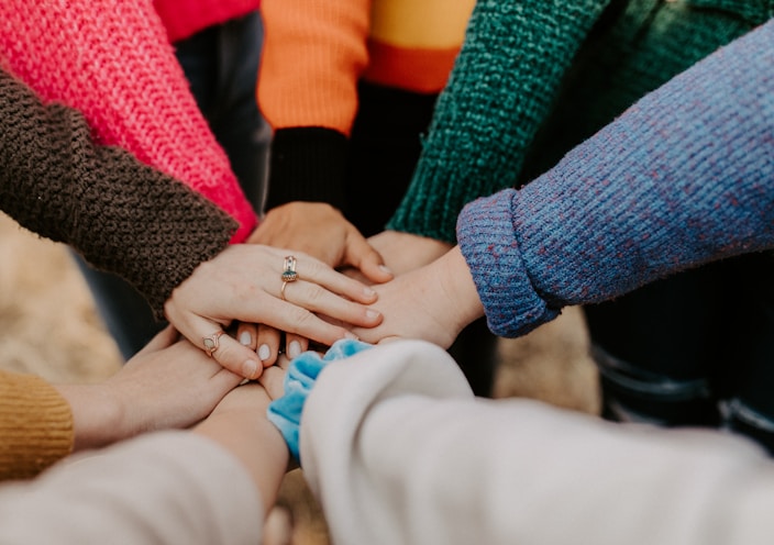 person in red sweater holding babys hand