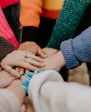 person in red sweater holding babys hand