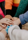 person in red sweater holding babys hand