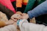 8 people placing hands on top of each other as a sign of team work