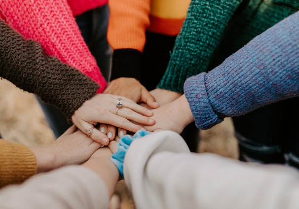 person in red sweater holding babys hand