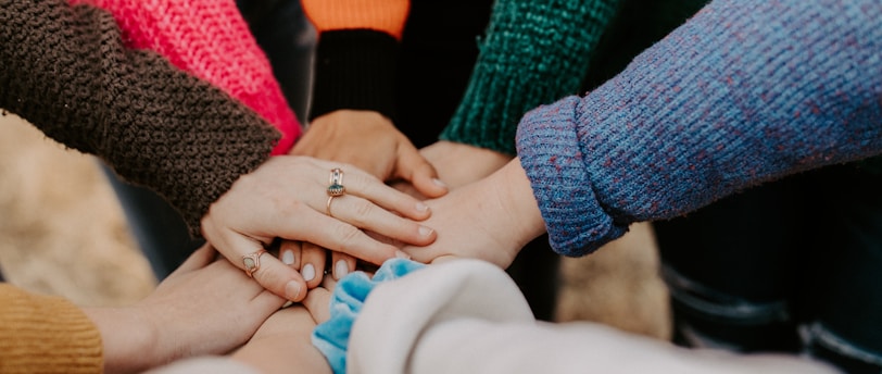 person in red sweater holding babys hand