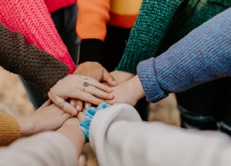 person in red sweater holding babys hand