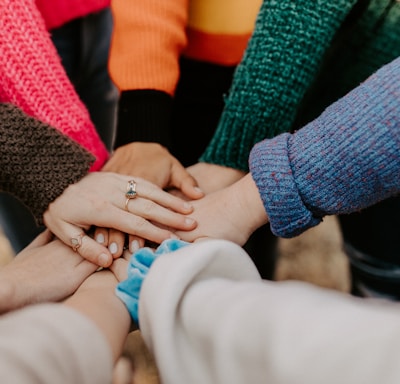 person in red sweater holding babys hand