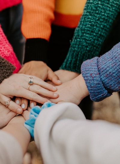 person in red sweater holding babys hand