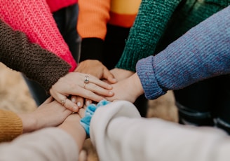 person in red sweater holding babys hand