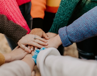 person in red sweater holding babys hand