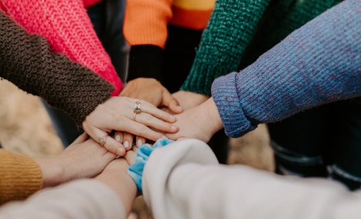 person in red sweater holding babys hand