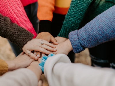 person in red sweater holding babys hand