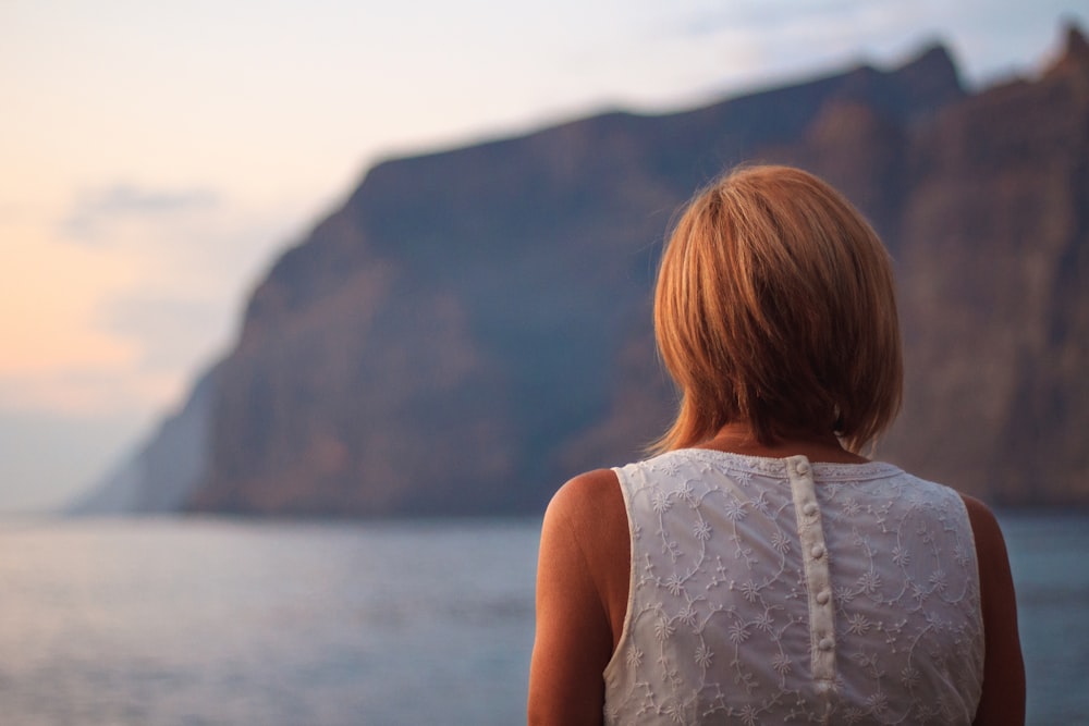 woman in white sleeveless shirt standing near body of water during daytime