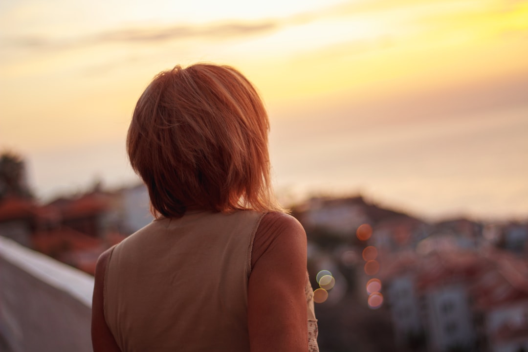 woman in white tank top looking at the sunset