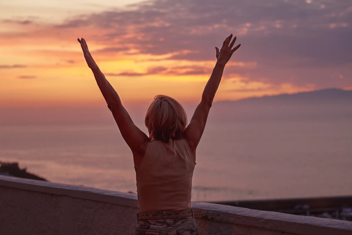 A woman raising her hands toward the sky outdoors