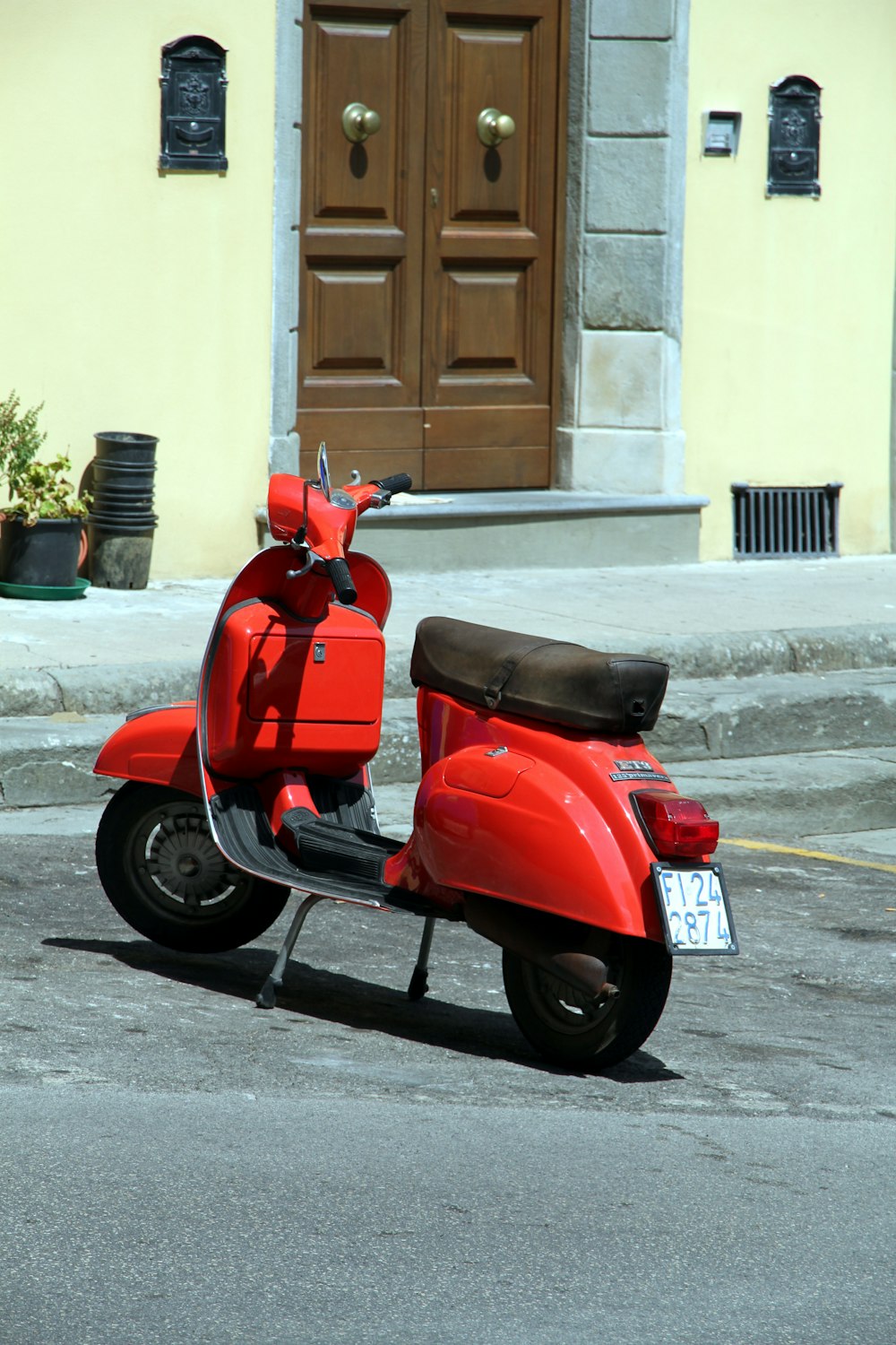 red and black motor scooter parked beside white concrete wall during daytime