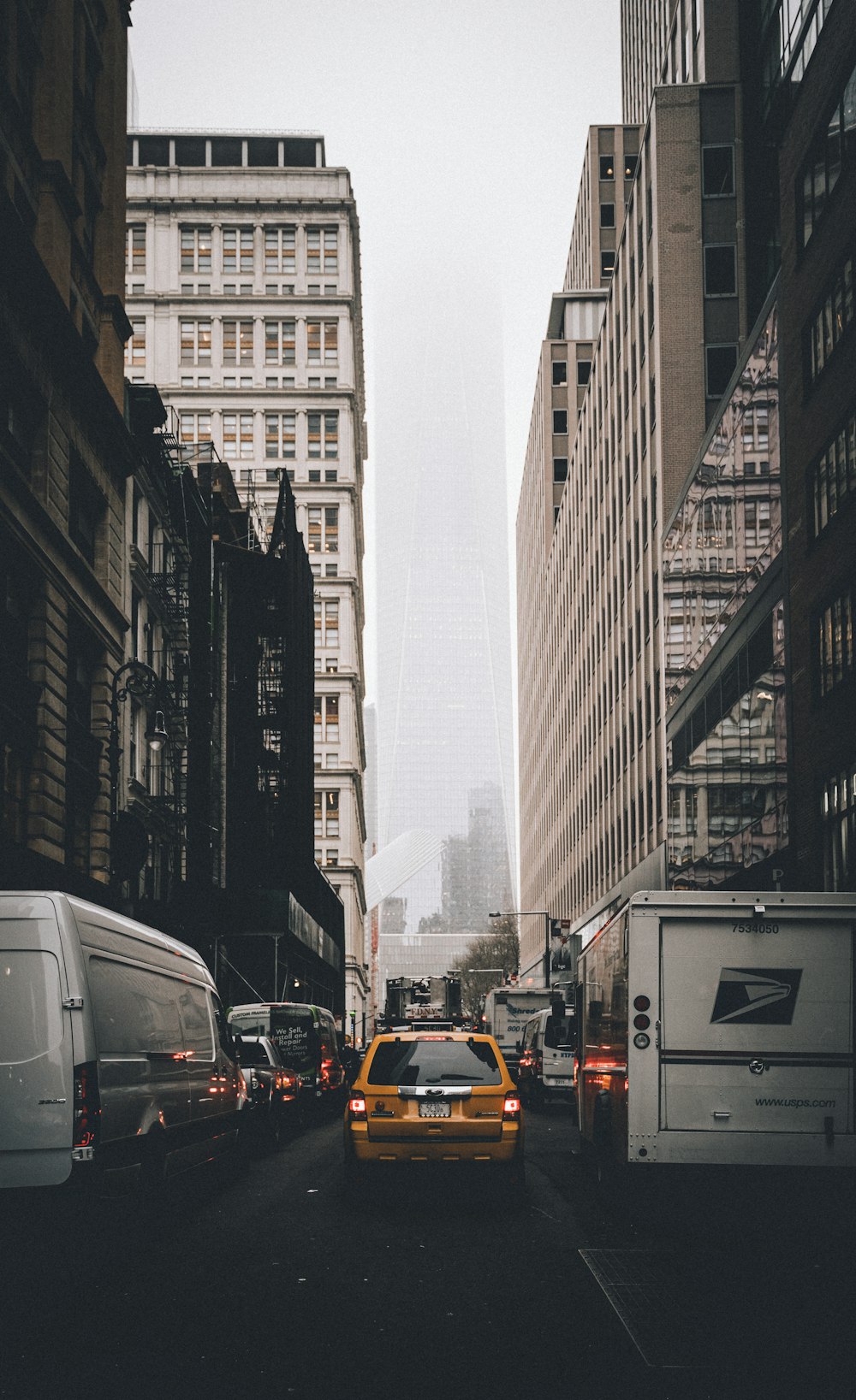 cars on road in between high rise buildings during daytime