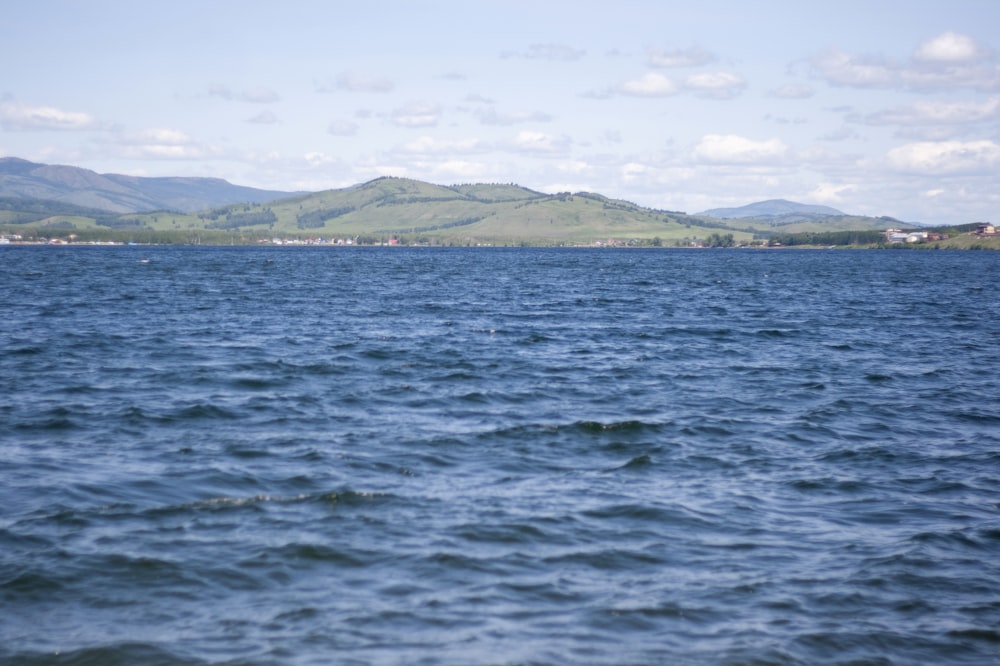 body of water near mountain during daytime