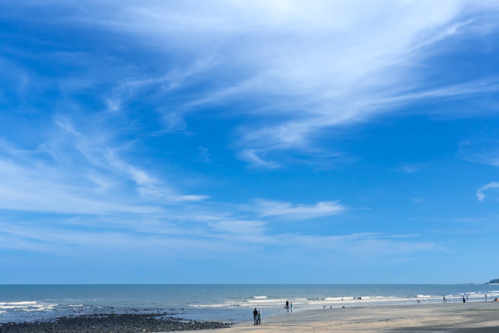 Menschen am Strand unter blauem Himmel und weißen Wolken tagsüber