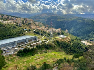 white concrete building on green mountain under white clouds during daytime