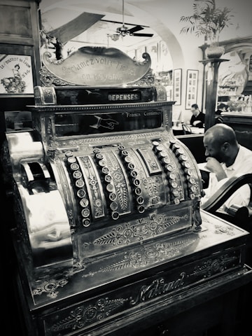 man in black suit standing beside brown and black wooden desk