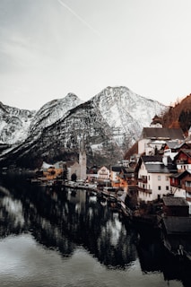 brown and white concrete houses near body of water and mountain