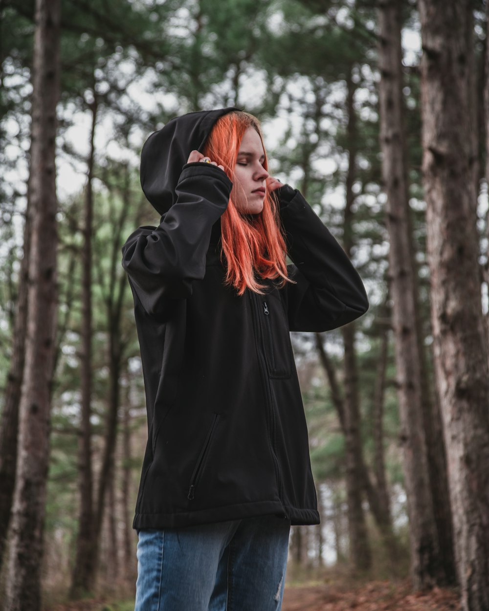 woman in black jacket standing in the woods