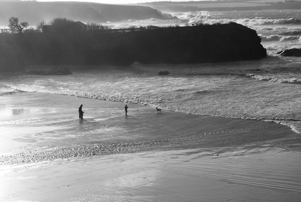 grayscale photo of 2 people walking on beach