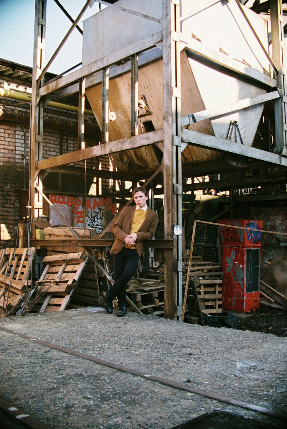 man in brown t-shirt and black pants standing on brown wooden ladder