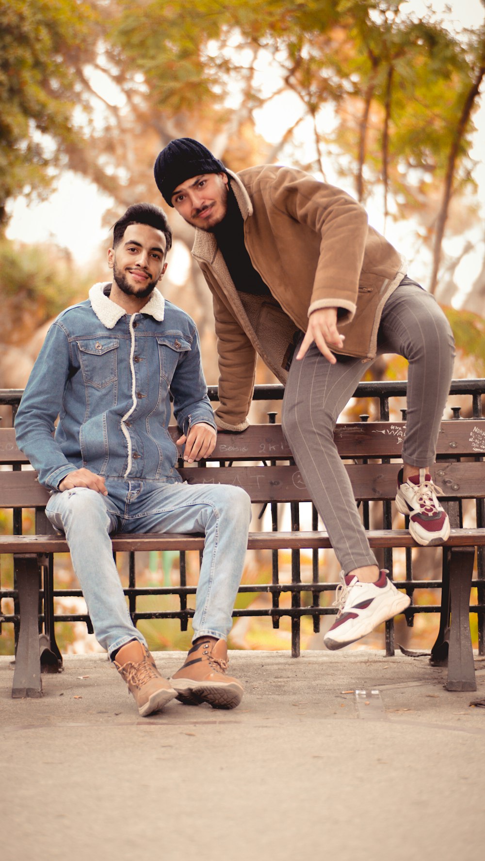 man in blue denim jeans sitting on brown wooden bench