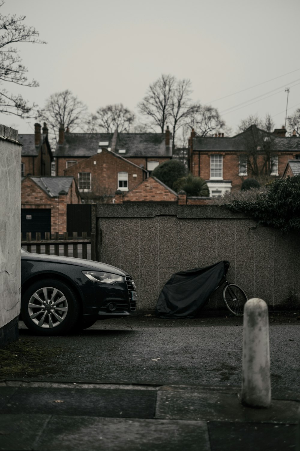 black car parked beside brown brick wall