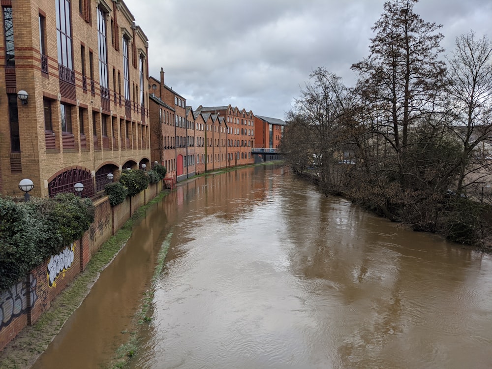 brown concrete building near river under white clouds during daytime