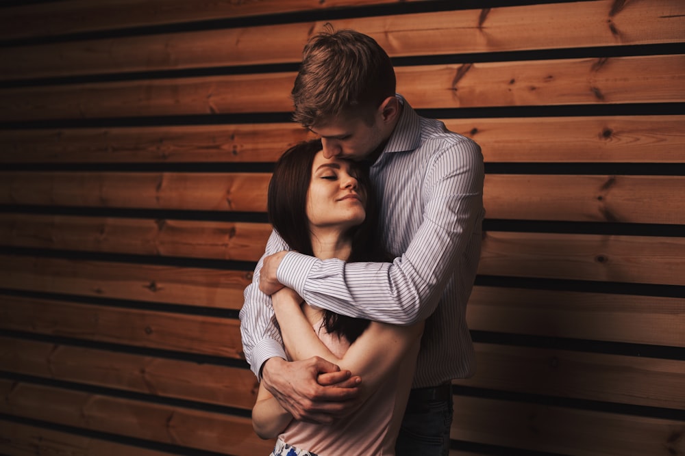 man in gray and white striped long sleeve shirt hugging woman in gray long sleeve shirt