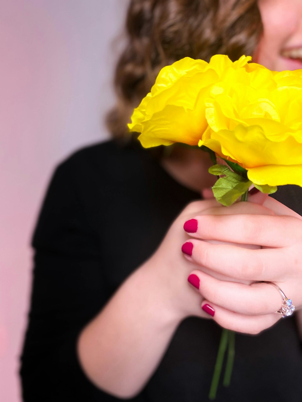 woman in black long sleeve shirt holding yellow flower