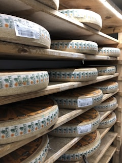 Close-up of traditional cheese wheels aging in a wooden cellar.