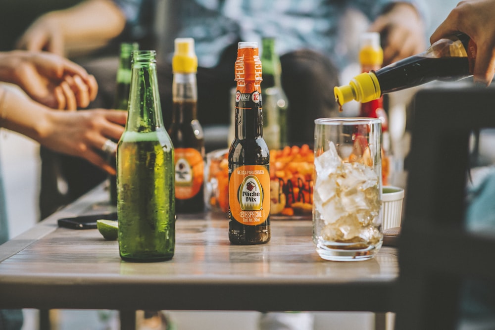 three bottles and drinking glass on table