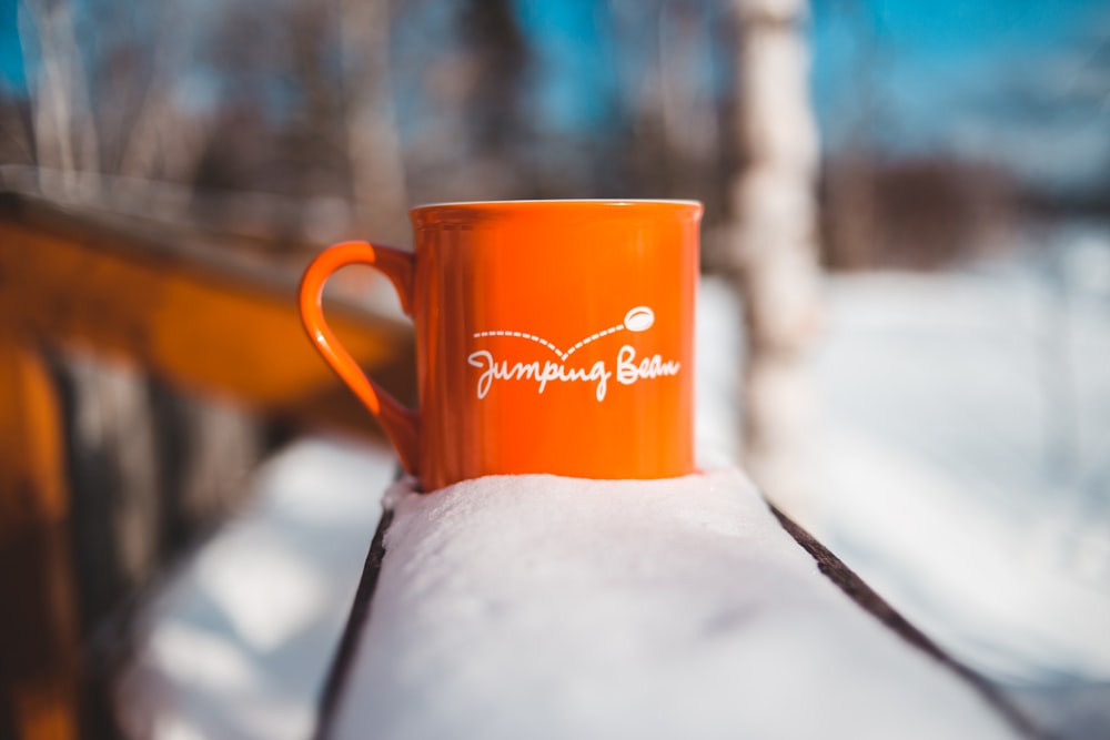 orange ceramic mug on white snow