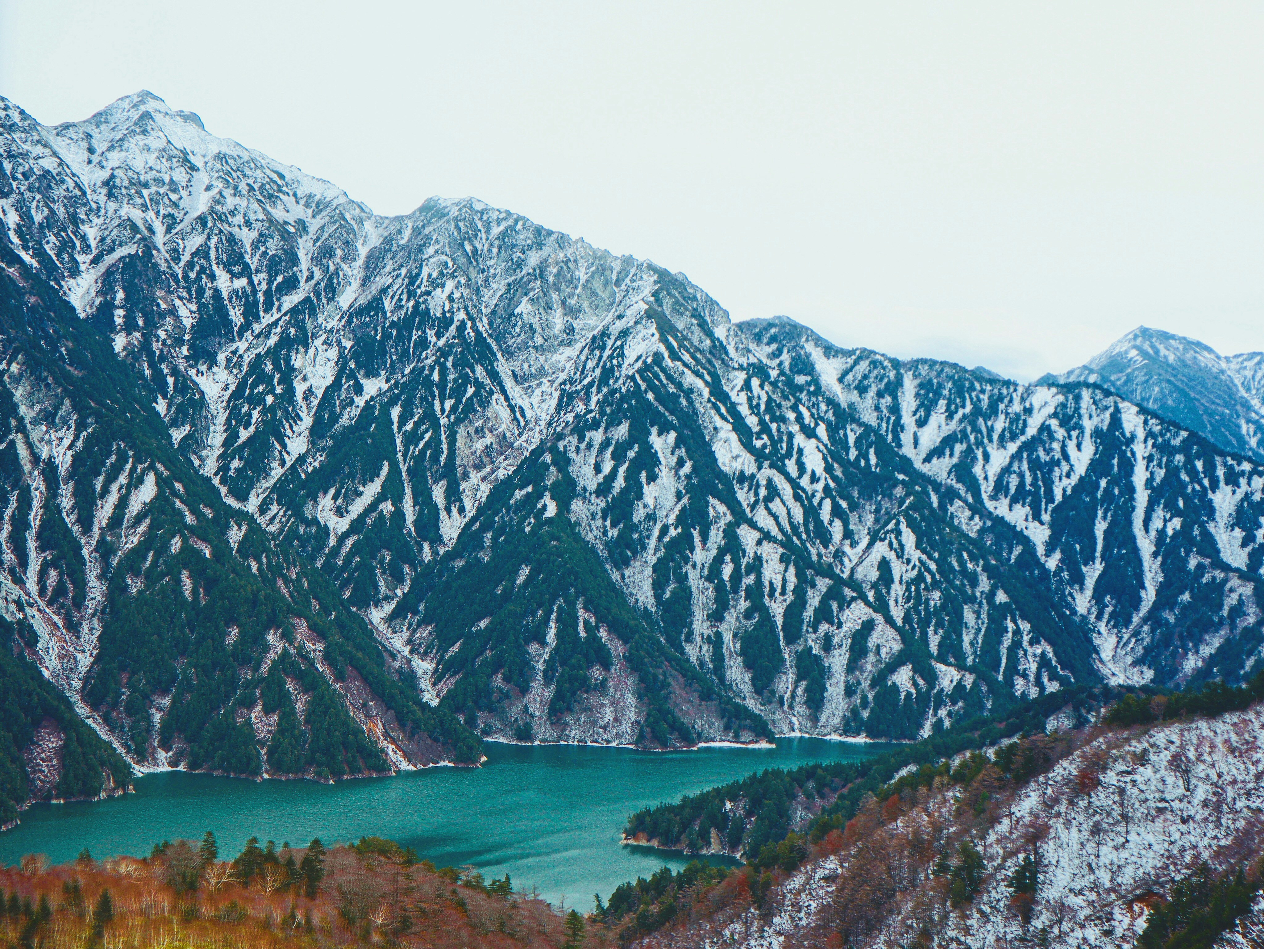 green lake near gray mountain during daytime