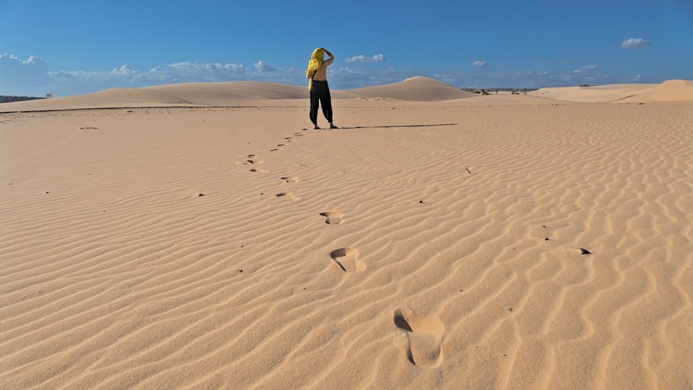homem na jaqueta amarela andando na areia durante o dia