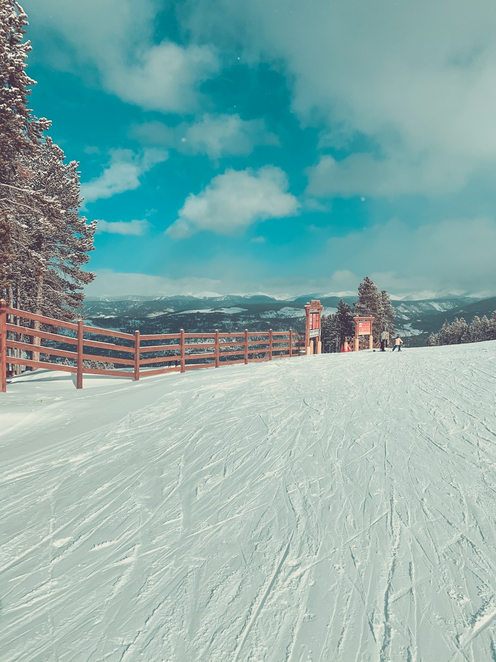 brown wooden fence on snow covered ground under blue sky and white clouds during daytime