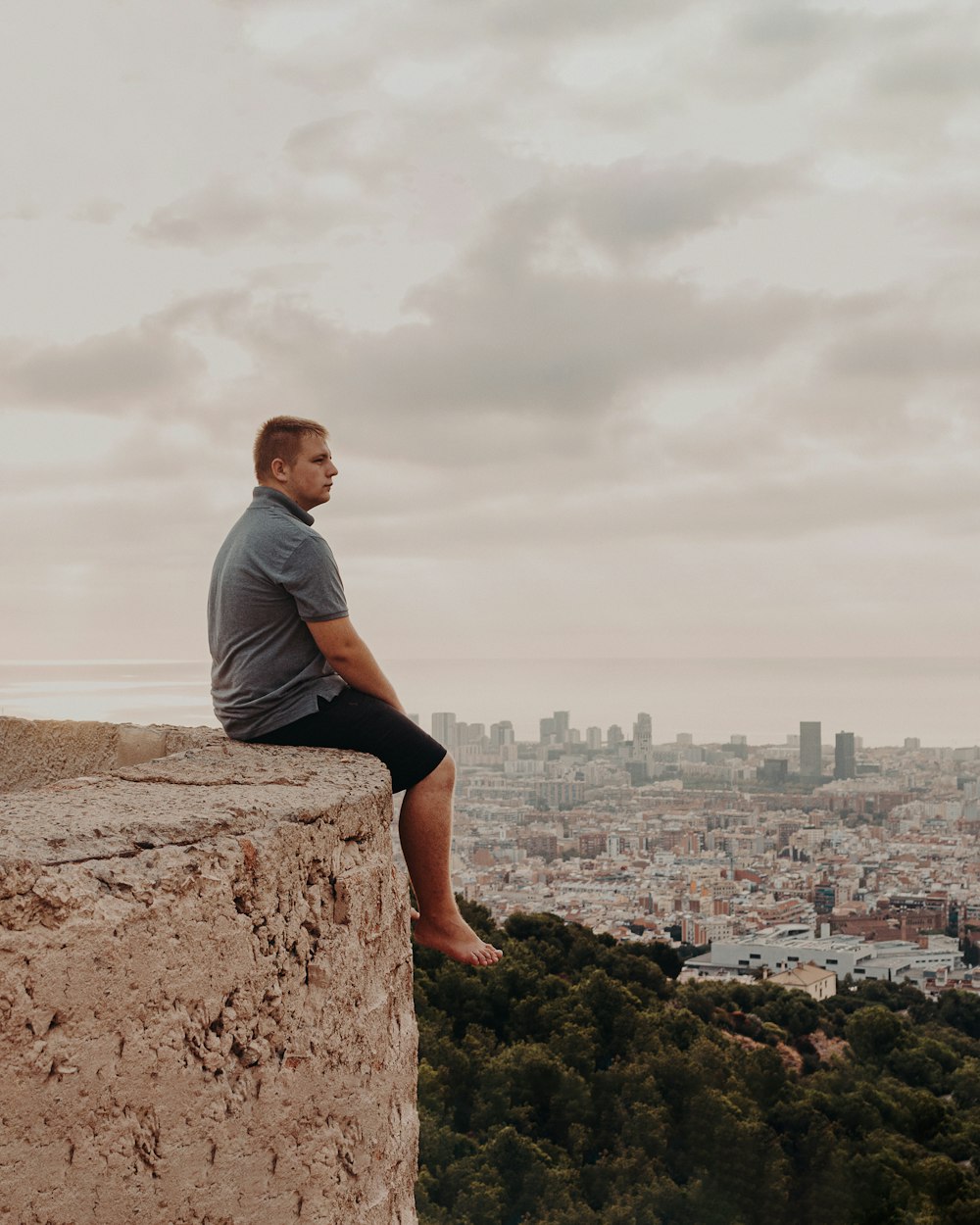 man in gray t-shirt sitting on brown rock during daytime