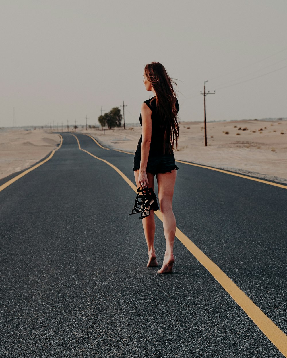 woman in black long sleeve shirt and black skirt standing on road during daytime