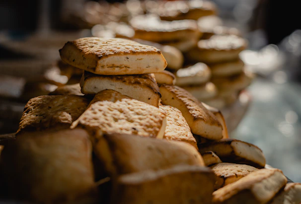 Close-up photo of warm, freshly baked cookies stacked on a rustic wooden board with soft natural light.