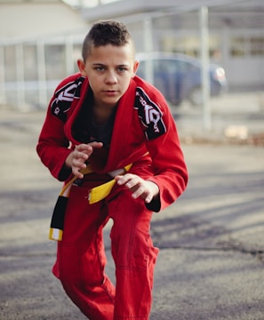 man in red and black nike jersey shirt and pants holding yellow and black smartphone