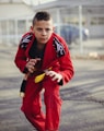 man in red and black nike jersey shirt and pants holding yellow and black smartphone