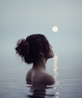 A serene woman bathed in soft moonlight, surrounded by delicate lunar symbols and natural textures.