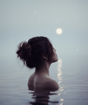 A serene woman bathed in soft moonlight, surrounded by delicate lunar symbols and natural textures.