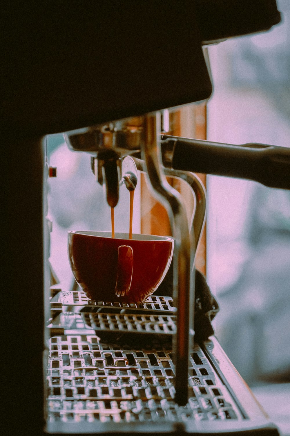 red and white ceramic cup on silver coffee maker