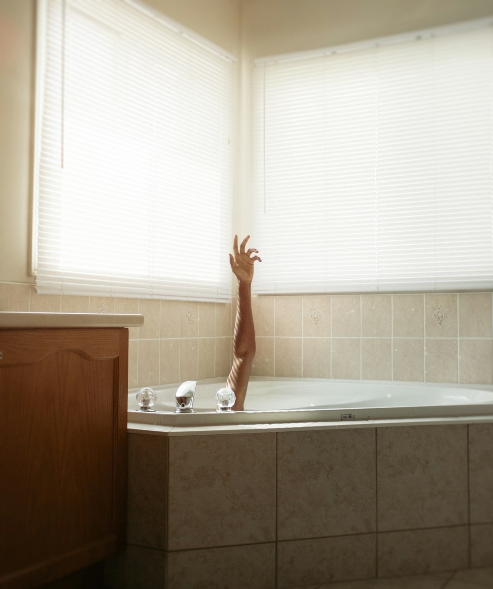 woman in bathtub near window blinds