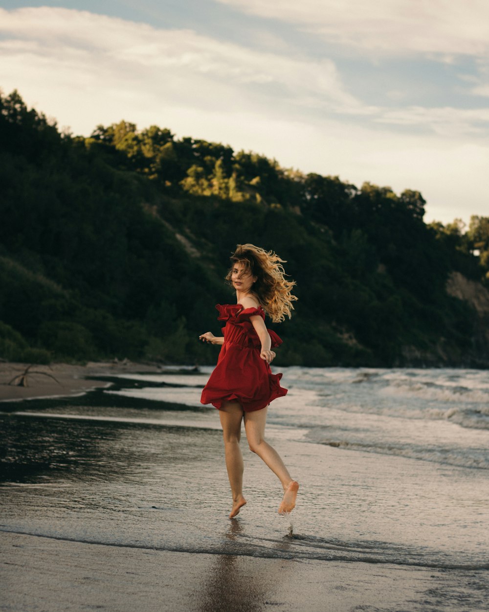 girl in red dress running on beach during daytime
