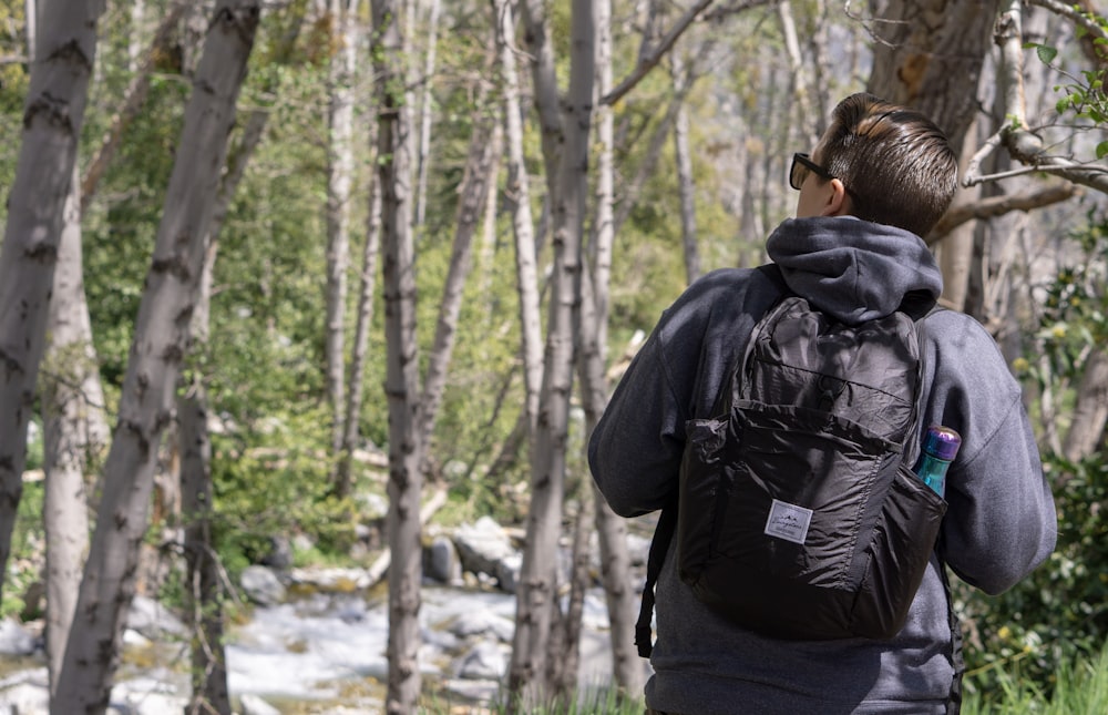 person in black jacket and black backpack standing in forest during daytime
